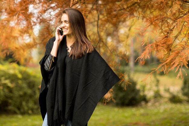 Vrouw met mobiele telefoon in het de herfstpark