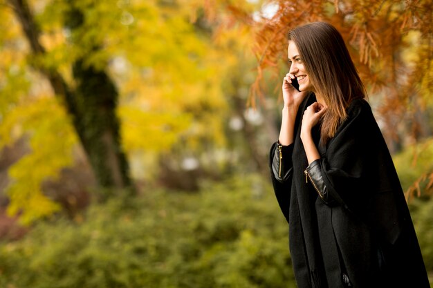 Vrouw met mobiele telefoon in het de herfstpark