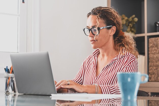 Vrouw met mobiele telefoon terwijl ze op tafel zit