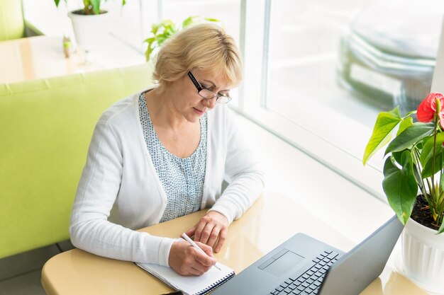 Vrouw met mobiele telefoon terwijl ze op tafel zit