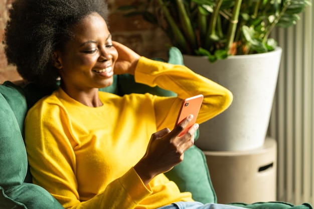 Vrouw met mobiele telefoon terwijl ze thuis zit