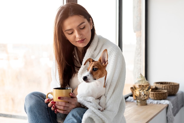 Vrouw met mok en hond in haar schoot