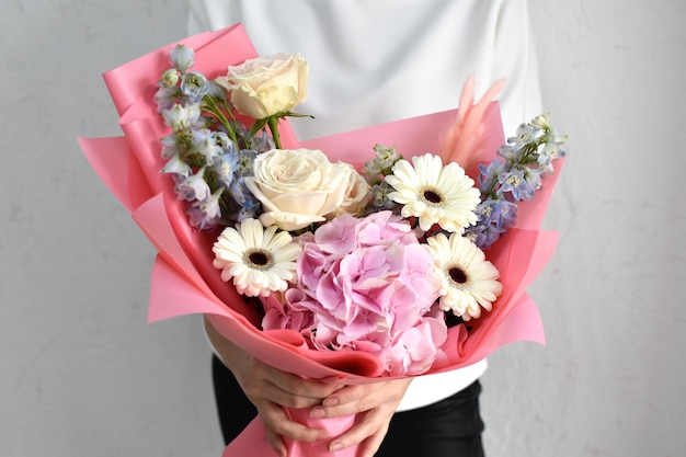 Vrouw met mooie bloemen in handen binnenshuis achtergrond boeket bloemen voor bloemenwinkel