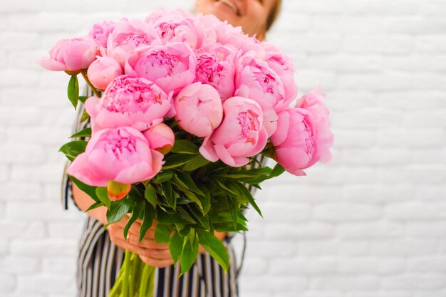 Vrouw met mooie pioenrozen. Bloemboeket in vrouwelijke handen.