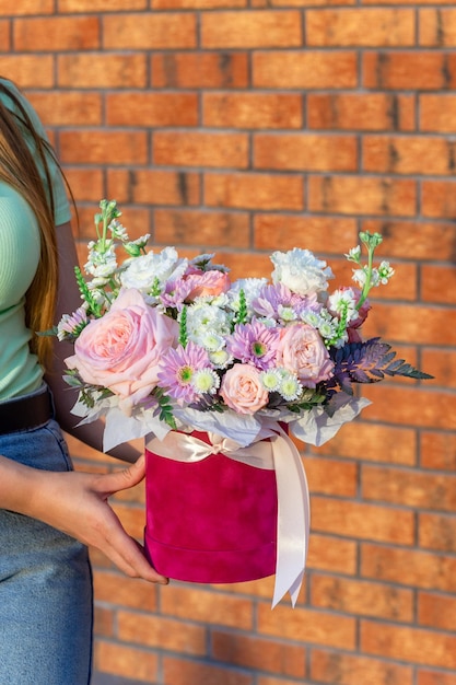 Vrouw met mooie rode fluwelen doos met verse rozen eustoma en andere bloemen versierd met linten