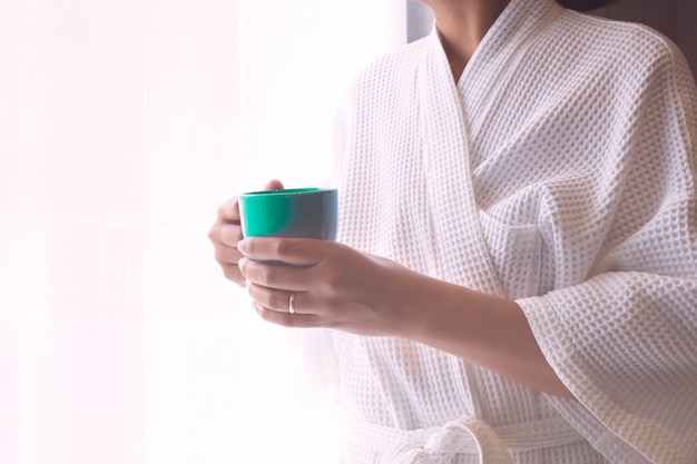 Vrouw met nachtkleding hand met koffiekopje.