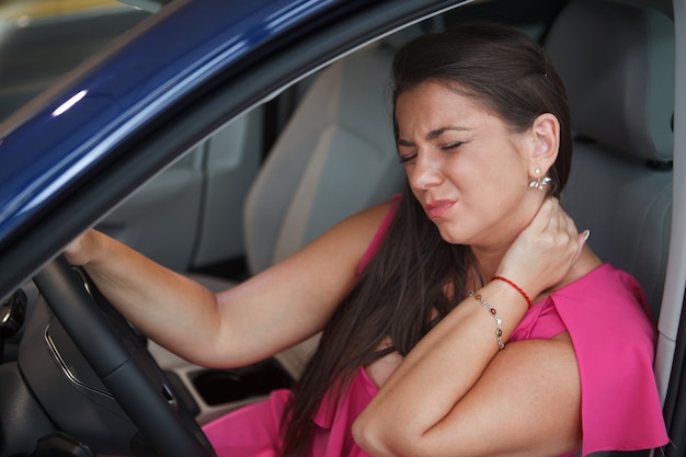 Vrouw met nekpijn, moe na lang rijden