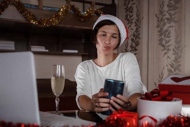 Vrouw met notebook thuis in kerstmuts Wintervakantie verkoop
