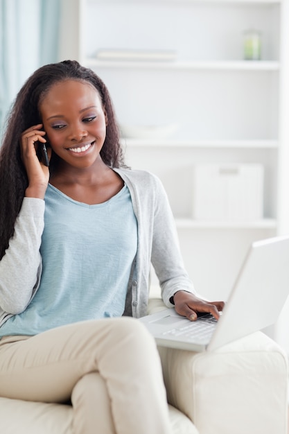 Vrouw met notitieboekje en mobiel op bank