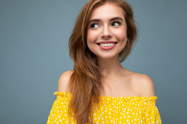 vrouw met oprechte emoties geïsoleerd op de achtergrondmuur met kopie ruimte, het dragen van stijlvolle gele zomerjurk. Gelukkig concept.