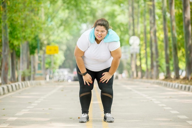 Vrouw met overgewicht die na het hardlopen op adem komt