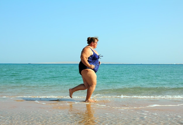 Vrouw met overgewicht die op het strand loopt