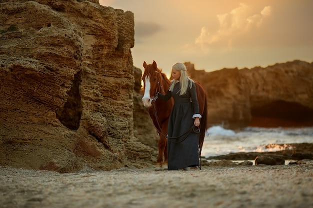 Vrouw met paard op rotsachtige kust