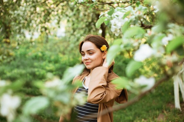 vrouw met paardebloem bloem in haar staande in groene tuin omgeven door bomen