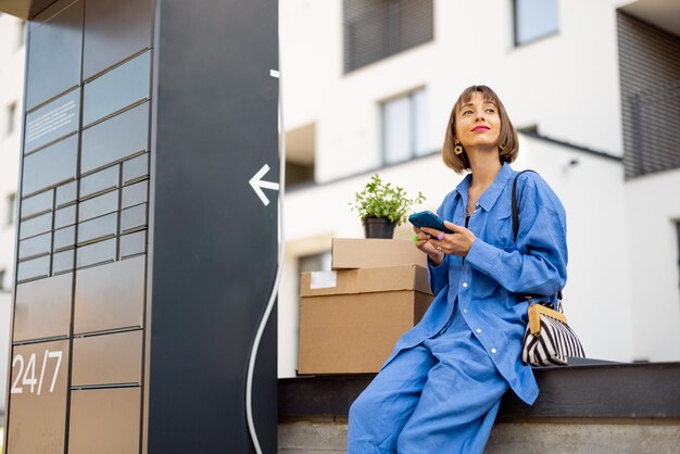 Vrouw met pakjes in de buurt van postkantoor machine buiten