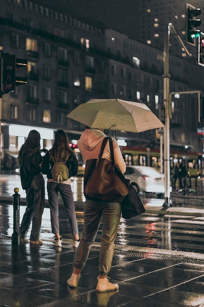 Vrouw met paraplu op regenachtige stadsstraat 's nachts