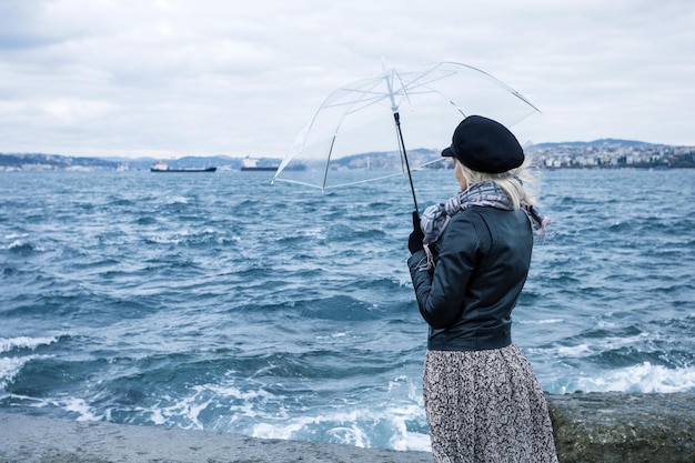 Vrouw met paraplu op winderige waterkant van Istanboel Turkije Concept van slecht weer