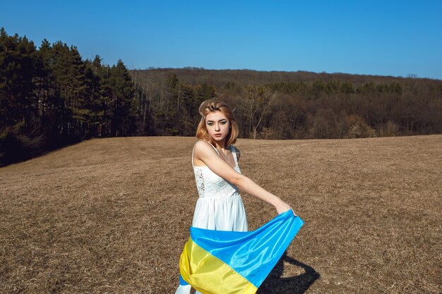 Vrouw met patriottische make-up verpakt in Oekraïense vlag Stand met Oekraïne concept