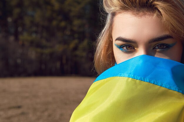 Vrouw met patriottische make-up verpakt in Oekraïense vlag Stand met Oekraïne concept