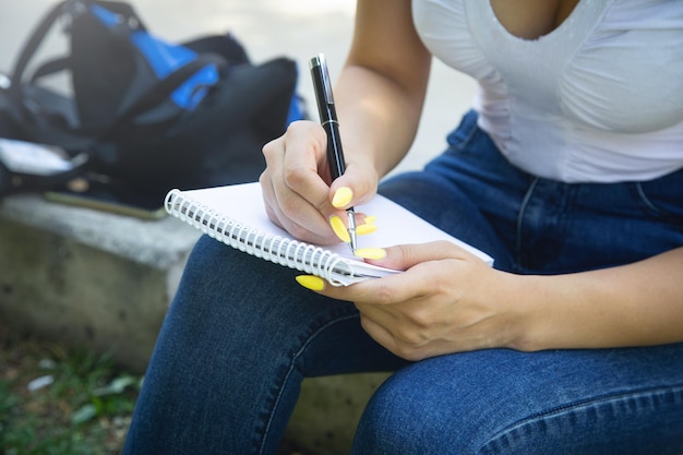 Vrouw met pen schrijven op Kladblok in de buitenlucht