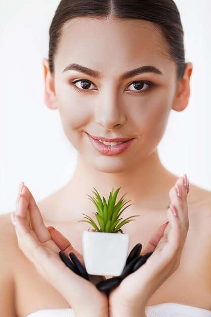 Vrouw met perfecte huid houdt een groene plant in haar handen