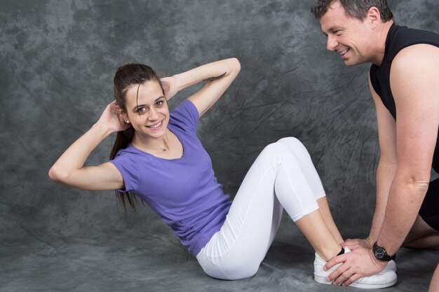 Vrouw met personal trainer doen sit-ups in de sportschool