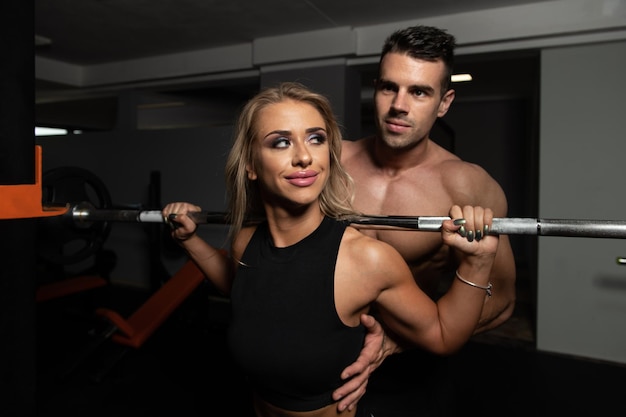 Vrouw met persoonlijke trainer bij barbell squat