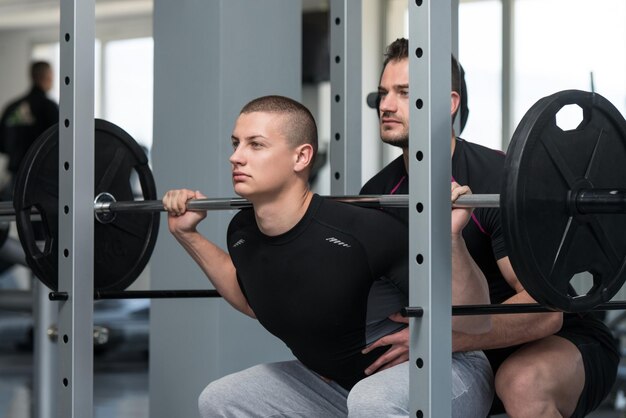 Vrouw met persoonlijke trainer bij barbell squat