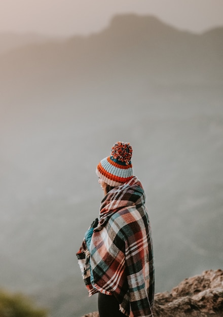 vrouw met poncho kijken naar de bergen