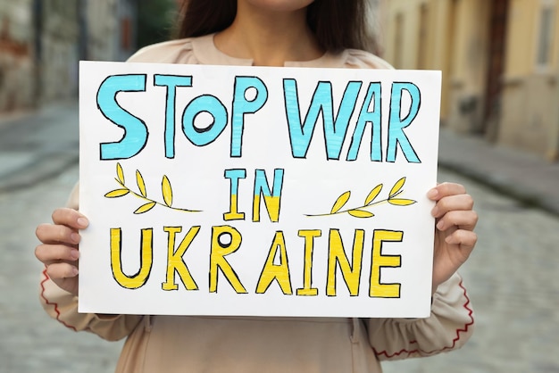 Vrouw met poster Stop oorlog in Oekraïne op straat close-up van de stad