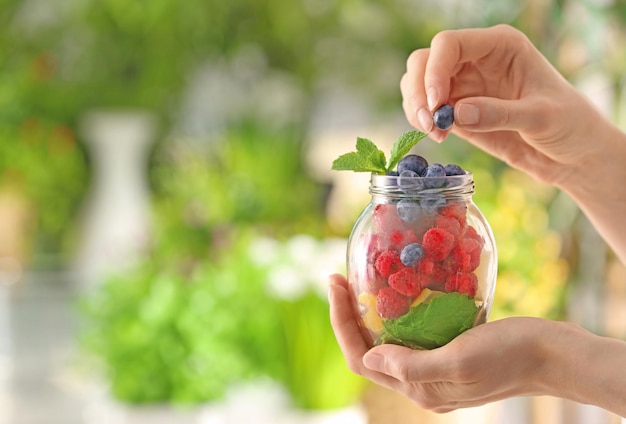 Vrouw met pot met fruit en bessen op onscherpe achtergrond