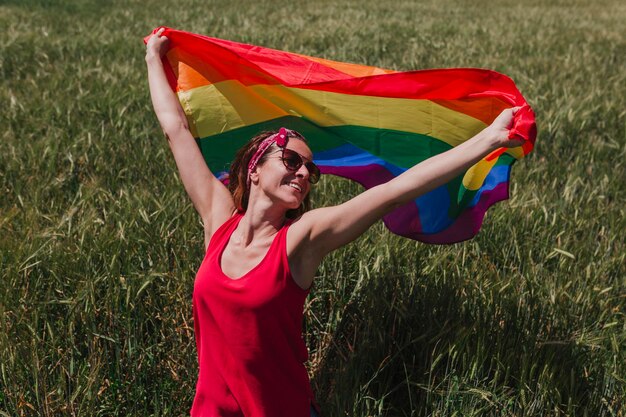 Vrouw met regenboogvlag die op het gazon staat