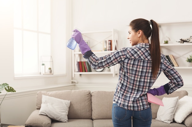 Vrouw met reinigingsapparatuur klaar om de kamer schoon te maken