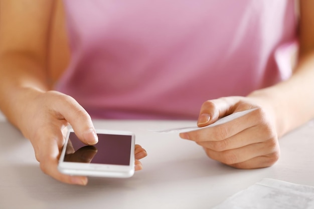 Vrouw met rekeningen en smartphone aan tafel berekening van de kosten