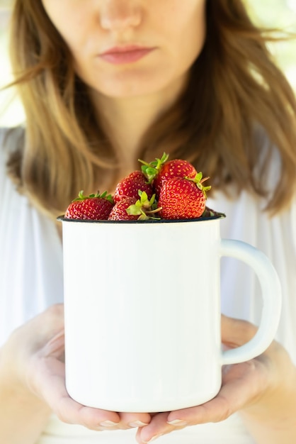 Foto vrouw met rijpe aardbeien in een geëmailleerde mok