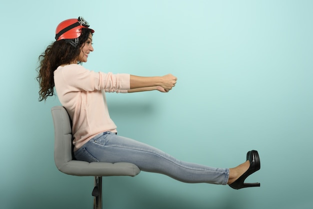 Vrouw met rode helm denkt een snelle auto te besturen. cyaan muur.