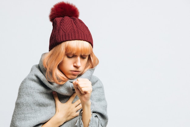 Foto vrouw met rode hoed hoesten, de eerste symptomen van ziekte voelen. bronchitis, griep