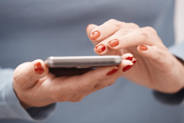 Vrouw met rode manicure met behulp van smartphone Horizontale foto