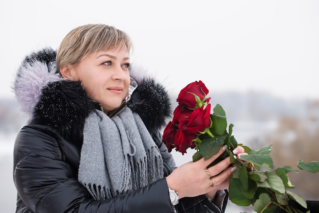 Vrouw met rode rozen buiten in de winter