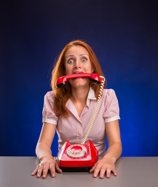 Vrouw met rode telefoon in haar mond