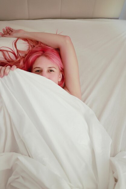 vrouw met roze haar op bed