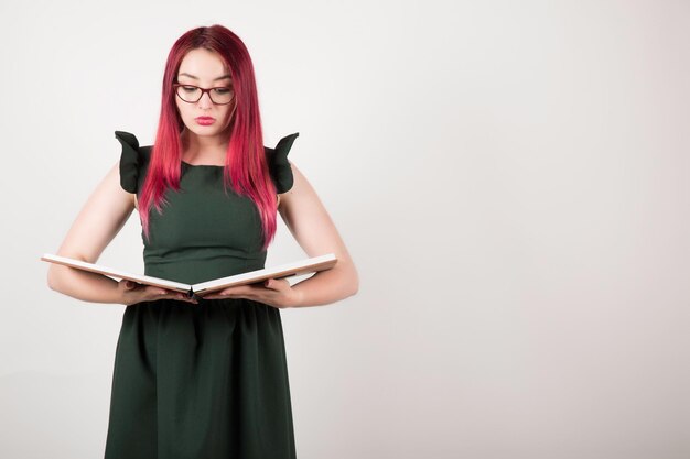 Vrouw met roze haar op wit boek houden