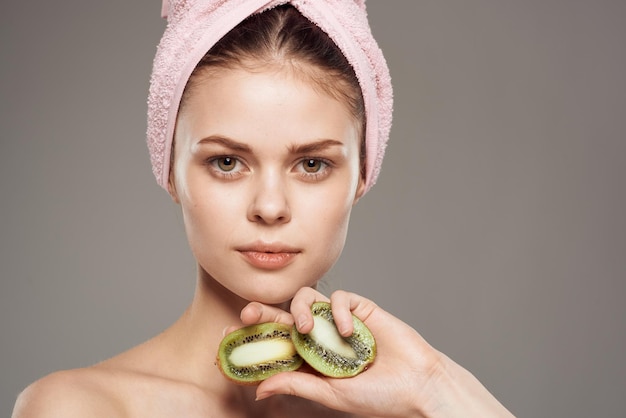 Vrouw met roze handdoek op haar hoofd blote schouders bijgesneden zicht op kiwi's in gezondheidshand