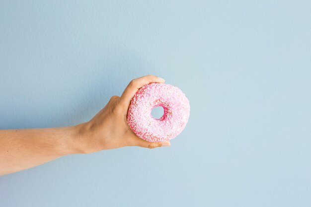 Vrouw met roze heerlijke donut op blauwe achtergrond.