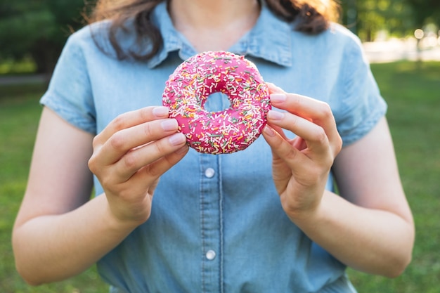 Vrouw met roze zoete donut. Koken concept, ongezonde voeding