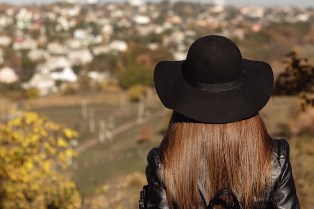 Vrouw met rugzak kijkt naar de stad in de herfstdag