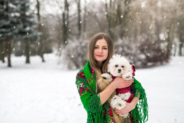 Vrouw met schattige witte hond in winter park