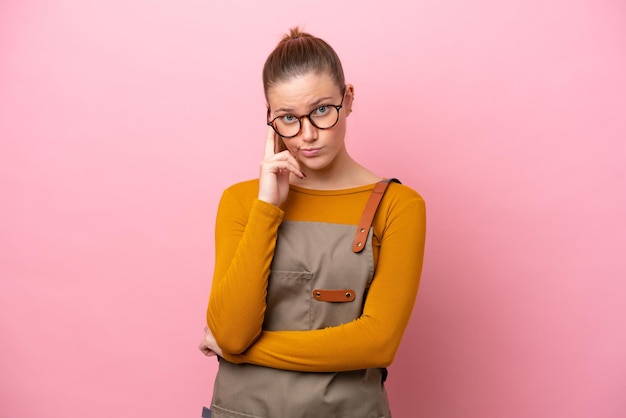 Vrouw met schort geïsoleerd op roze achtergrond denken een idee