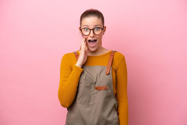 Foto vrouw met schort geïsoleerd op roze achtergrond met verrassing en geschokte gezichtsuitdrukking