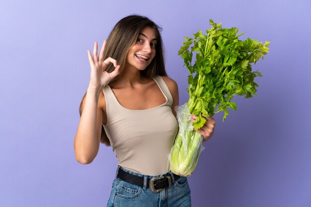 Vrouw met selderij geïsoleerd op paars